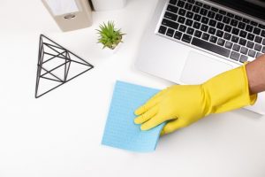 Hand wiping office desk with disinfection solution